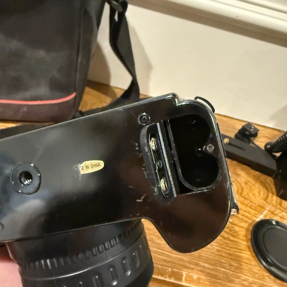 Vintage Canon camera with a flash attachment and carrying case.